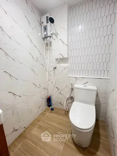 Modern bathroom with sleek toilet and shower in stylishly tiled space.