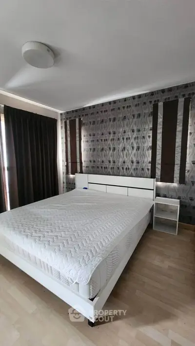 Spacious bedroom with modern decor and large window for natural light.