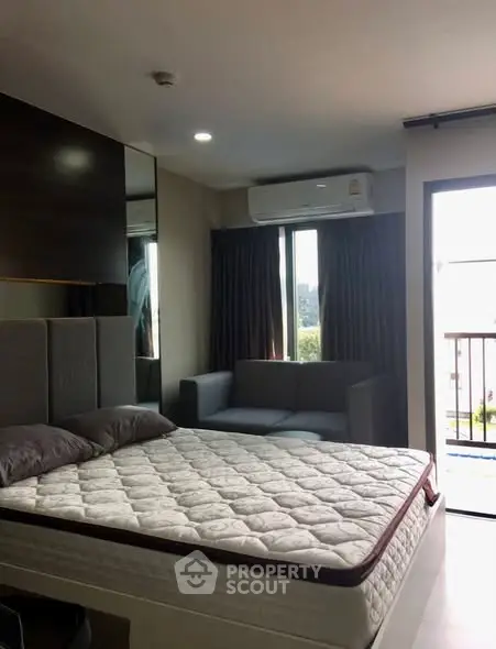 Modern bedroom with large window and balcony access in a stylish apartment.