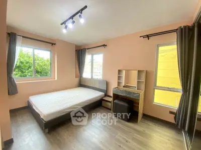 Spacious bedroom with large windows and modern furnishings in a well-lit apartment.