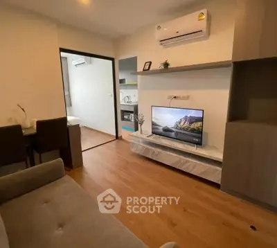 Modern living room with wooden flooring and air conditioning, featuring a cozy sofa and flat-screen TV.