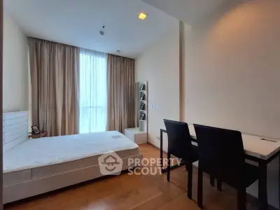 Spacious bedroom with modern decor and natural light, featuring a comfortable bed and work desk.