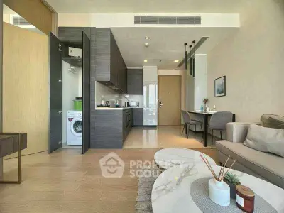 Modern open-plan living room with sleek kitchen and cozy dining area, featuring a washing machine and stylish decor.