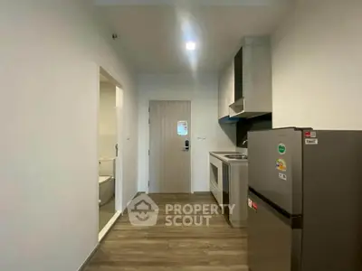 Modern compact kitchen with sleek appliances and wooden flooring in a cozy apartment.