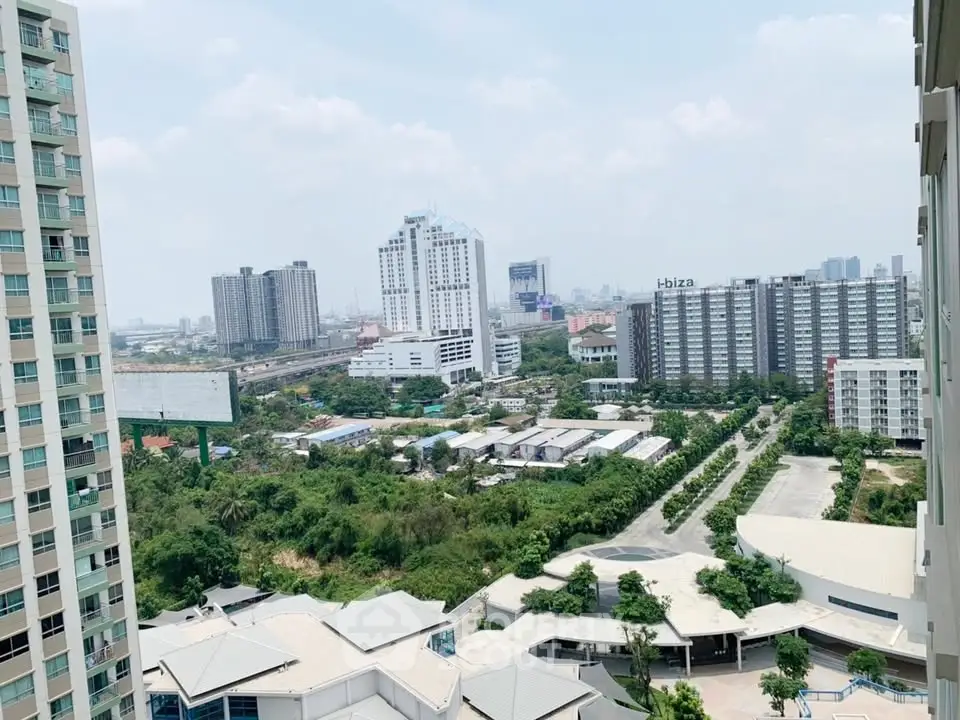 Stunning cityscape view from high-rise balcony overlooking lush greenery and modern buildings.