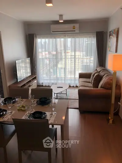 Modern living room with dining area and city view, featuring cozy sofa and elegant decor.