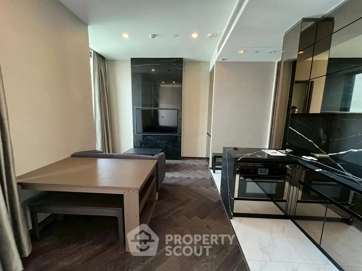 Modern living room with sleek furniture and built-in TV, featuring a stylish open kitchen layout.