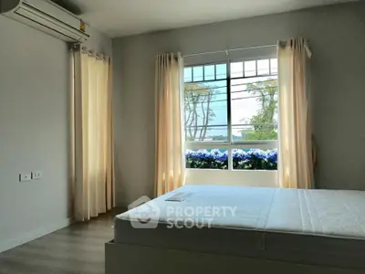 Bright bedroom with large window and air conditioning, offering a serene view and natural light.