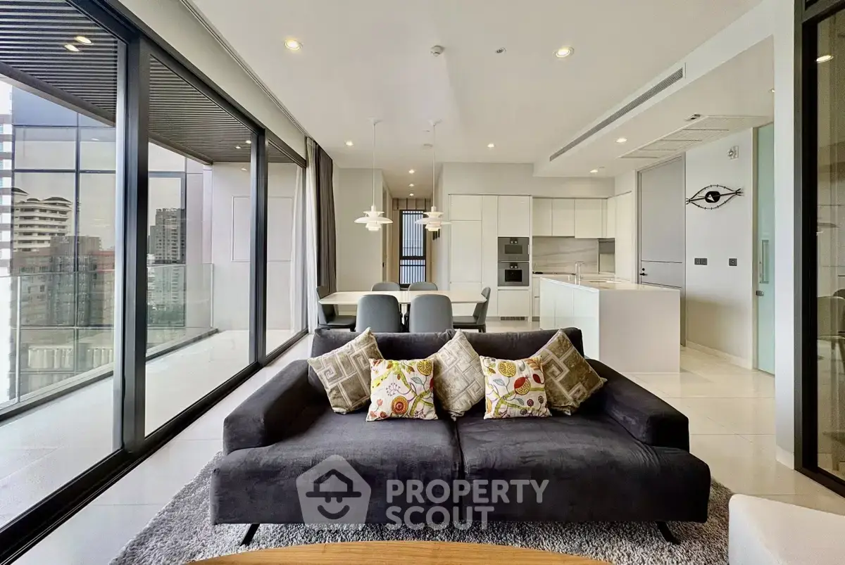 Luxurious modern living room with floor-to-ceiling windows and open kitchen in high-rise apartment.