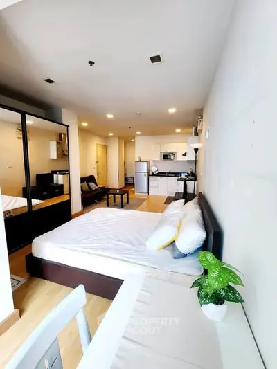 Modern studio apartment with open layout, featuring a cozy bed, sleek kitchen, and stylish decor.