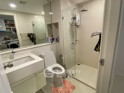 Modern bathroom with glass shower, sleek sink, and toilet in a contemporary apartment.