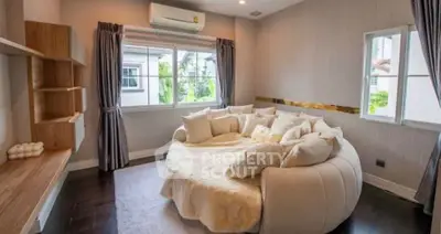 Luxurious living room with unique round sofa and large windows offering natural light.