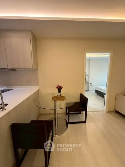 Modern open-layout kitchen with dining area and view into bedroom, featuring sleek design and cozy ambiance.