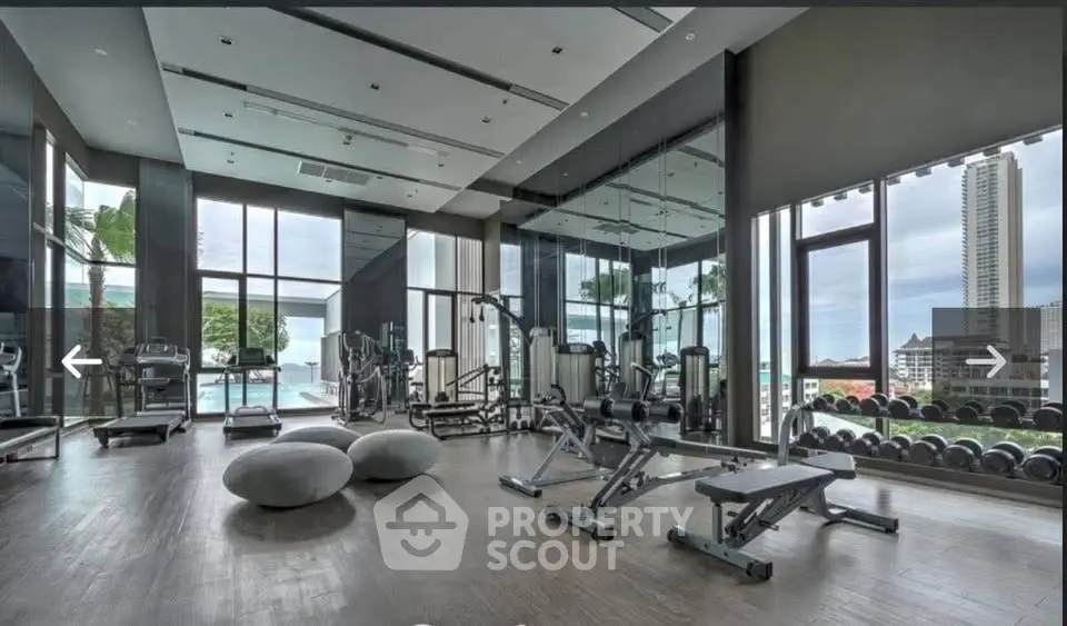 Luxurious gym with modern equipment and stunning city view in high-rise building.
