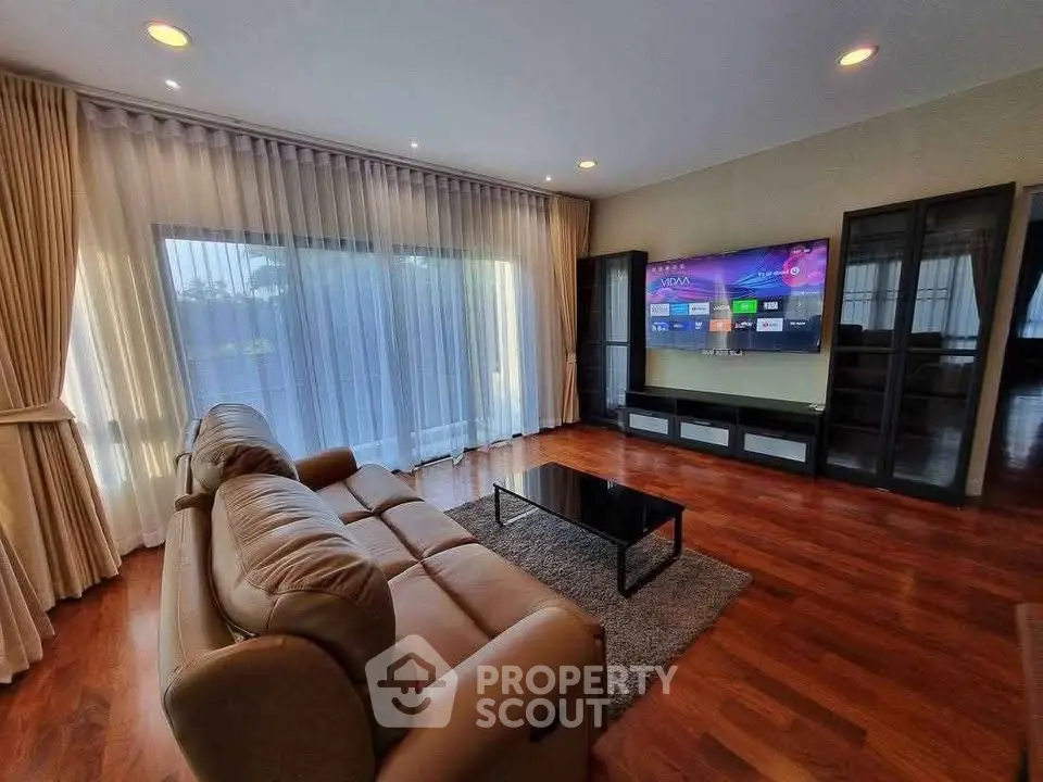 Spacious living room with elegant decor, large windows, and modern entertainment setup.
