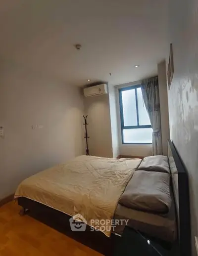 Cozy bedroom with natural light and modern furnishings in a stylish apartment.