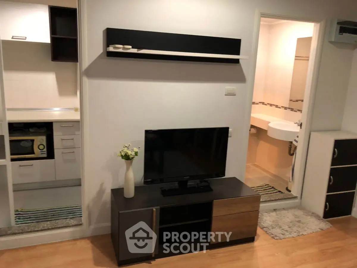 Modern living room with sleek TV stand and open kitchen layout in stylish apartment.