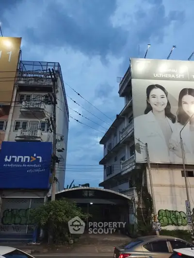 Urban street view with residential building and large advertisement banners at dusk.