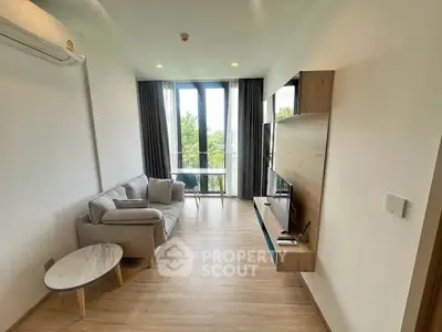 Modern living room with sleek furniture and large windows offering natural light and greenery view.