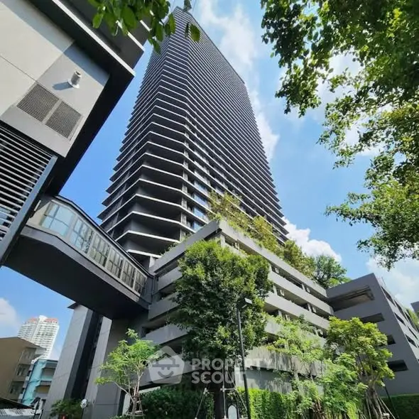Modern high-rise building with lush greenery and skybridge in urban setting