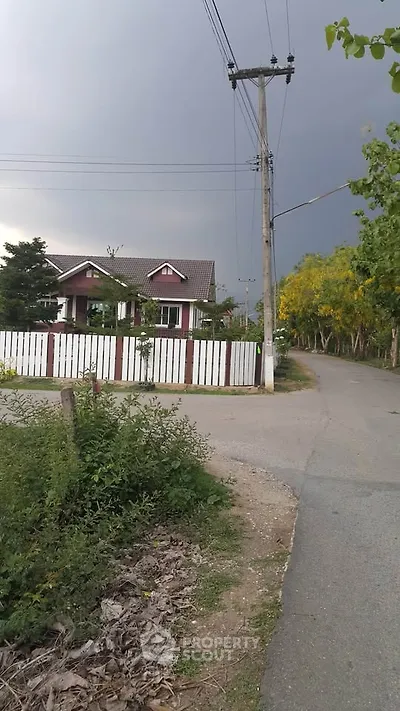 Charming suburban house with white picket fence and lush greenery on a quiet street.