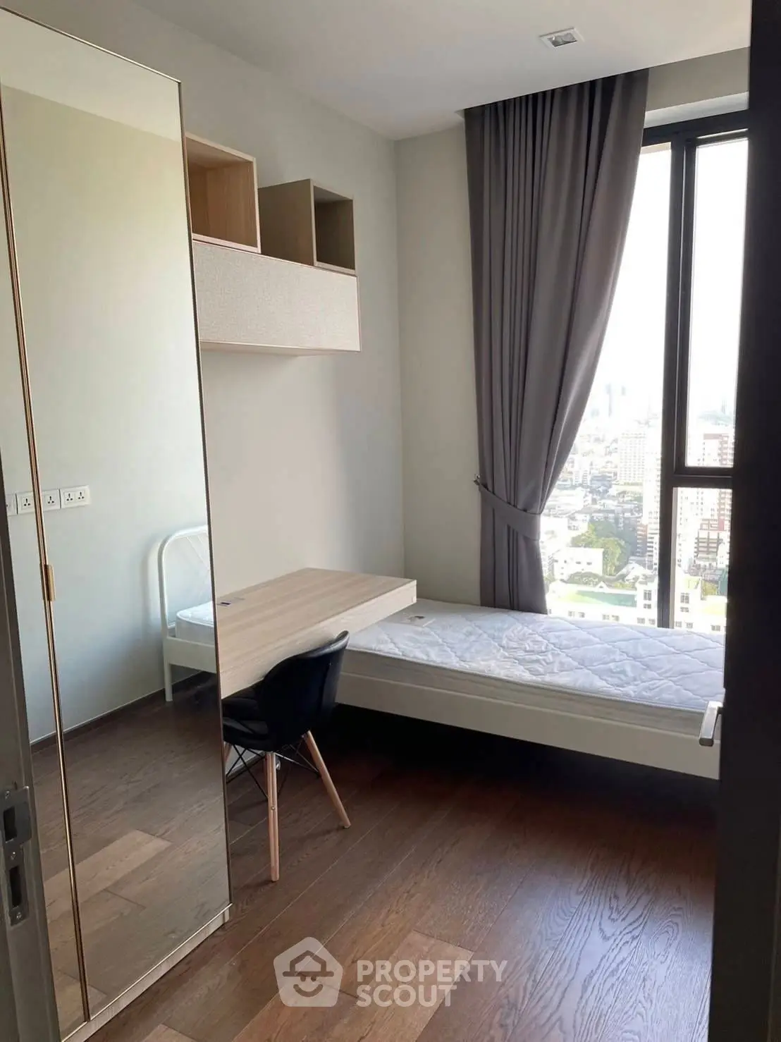 Modern bedroom with city view, sleek furnishings, and large window for natural light.