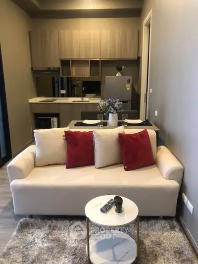 Cozy living room with modern kitchen, featuring plush sofa and stylish decor.