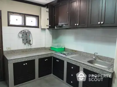 Spacious kitchen with dark wood cabinets and granite countertops