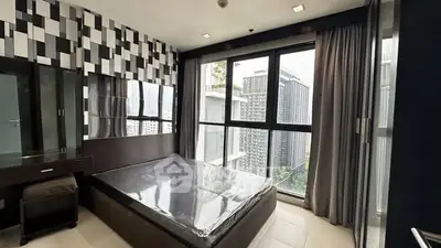 Modern bedroom with large windows and city view in high-rise apartment.