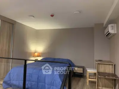 Modern bedroom with blue bedding, sleek wooden furniture, and air conditioning unit.