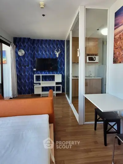 Modern living room with vibrant blue accent wall and open kitchen layout