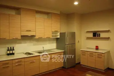 Modern kitchen with sleek cabinetry and stainless steel fridge in a cozy apartment.