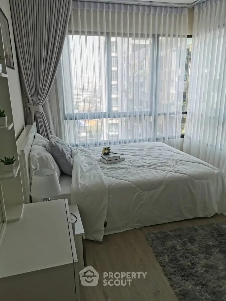 Bright and cozy bedroom with large windows and modern decor in a high-rise apartment.
