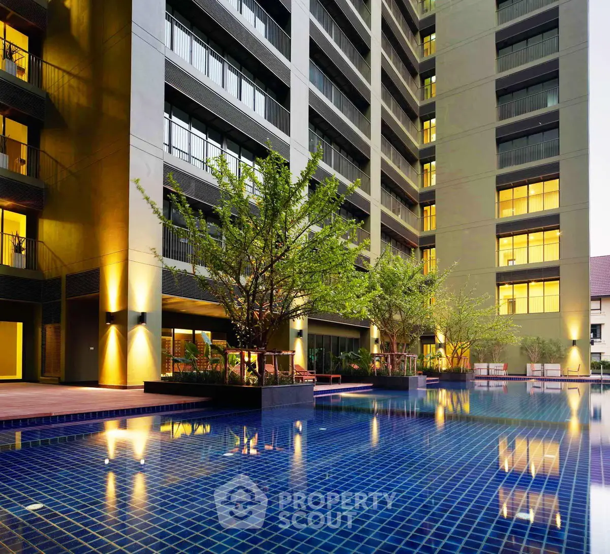 Luxurious apartment building with illuminated pool and modern exterior design.