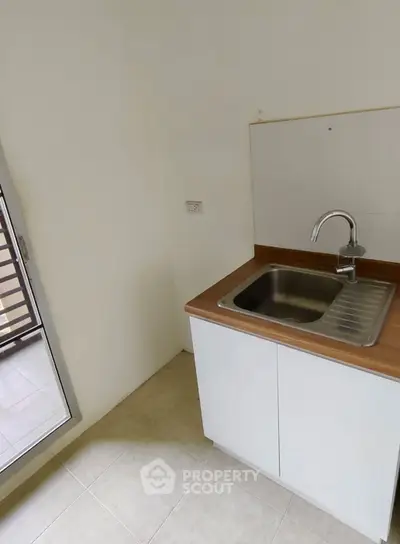 Compact kitchen area with modern sink and wooden countertop, ideal for small apartments.