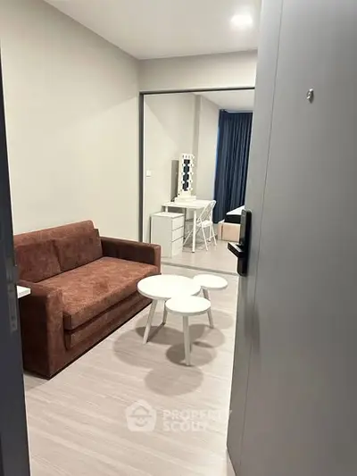 Modern living room with brown sofa and stylish white coffee tables in a cozy apartment.