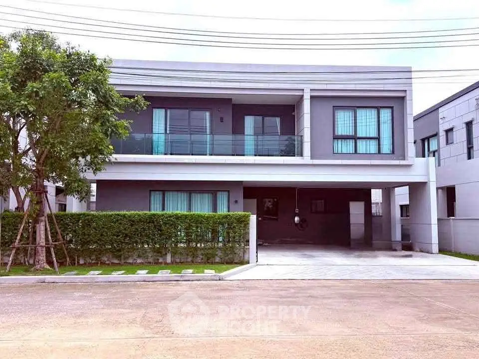 Modern two-story house with large windows and a spacious driveway in a suburban neighborhood.