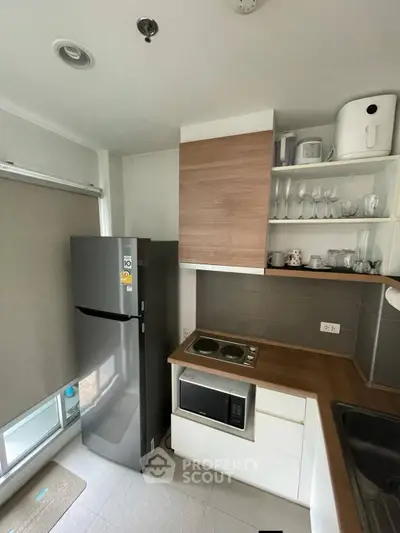 Modern kitchen with sleek appliances and wooden cabinetry in a compact layout.