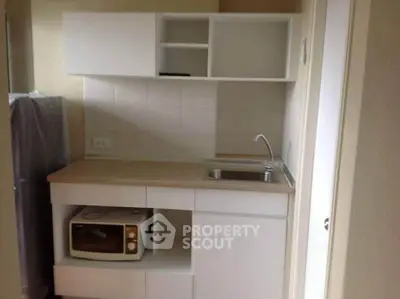 Compact kitchen with microwave and sink in modern apartment