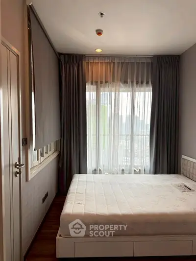 Cozy bedroom with large window and modern decor in urban apartment.