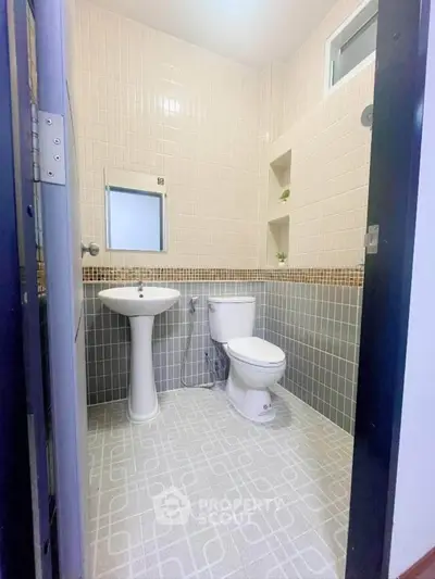 Modern bathroom with pedestal sink and tiled walls in a stylish real estate property.
