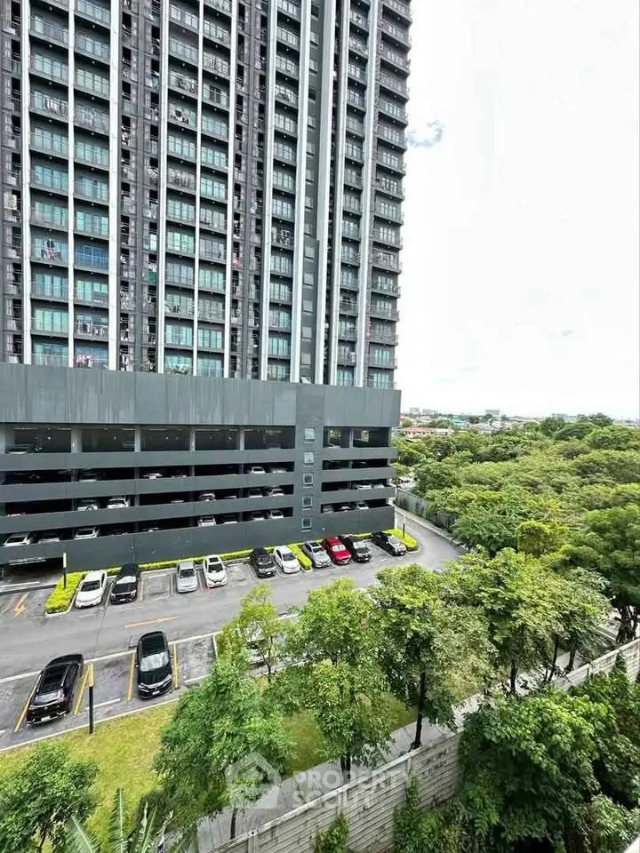 Modern high-rise building with parking and lush greenery view