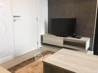 Modern living room with sleek TV stand and flat-screen TV, featuring minimalist decor and neutral tones.
