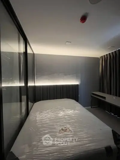 Modern bedroom with sleek design and ambient lighting, featuring a bed and desk setup.