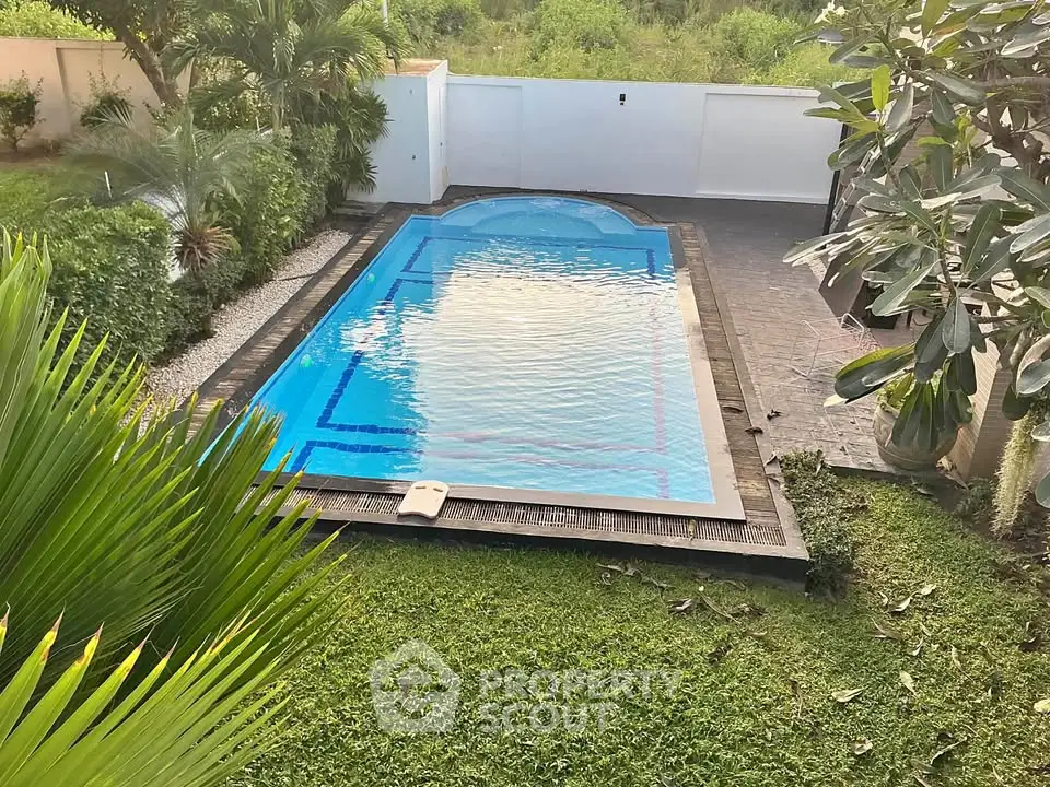 Luxurious backyard with a pristine swimming pool and lush greenery, perfect for relaxation and entertainment.