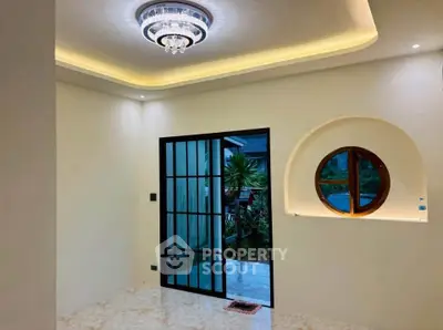 Elegant interior with modern lighting and unique window design, featuring a stylish sliding door opening to a garden view.