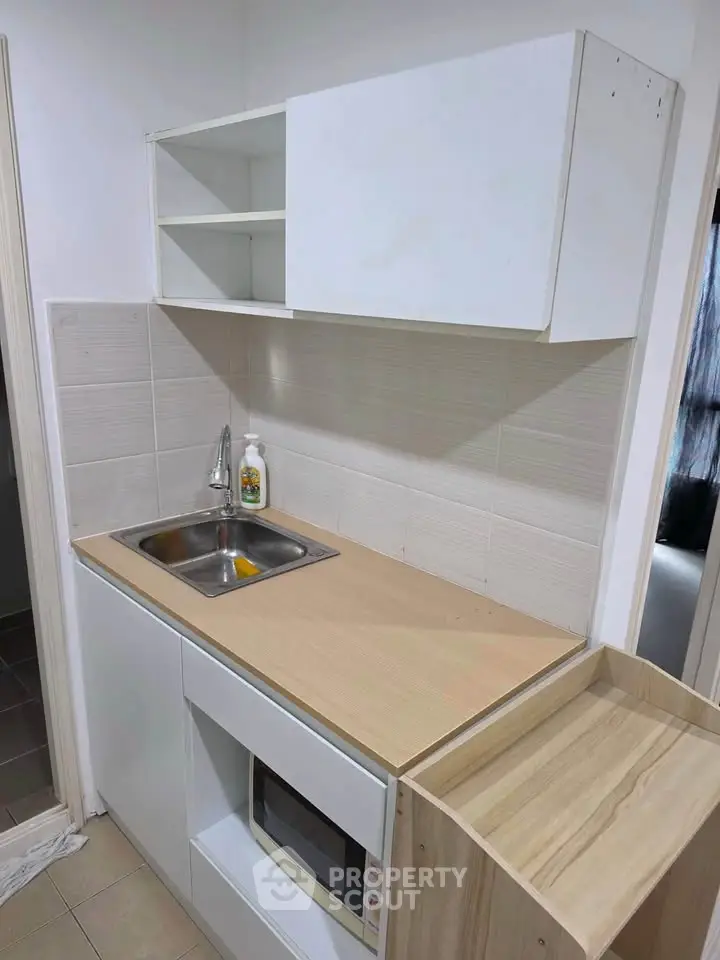 Compact kitchen with modern cabinetry and built-in microwave, ideal for small apartments.
