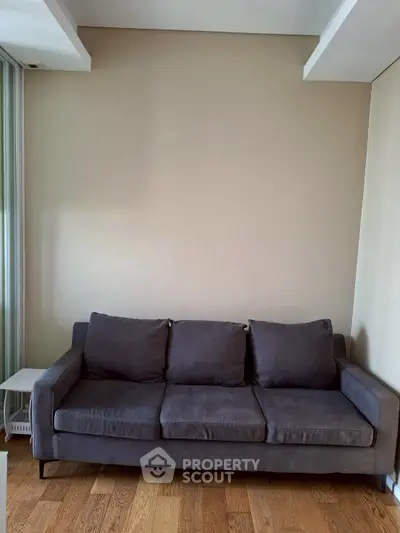 Modern living room with sleek dark sofa and wooden flooring, perfect for stylish urban living.