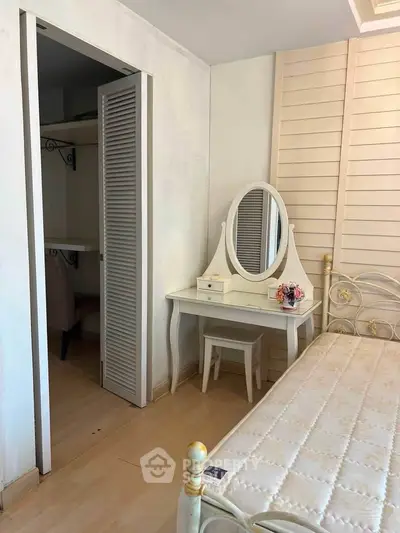 Charming bedroom with elegant vanity and cozy closet space, perfect for a serene retreat.
