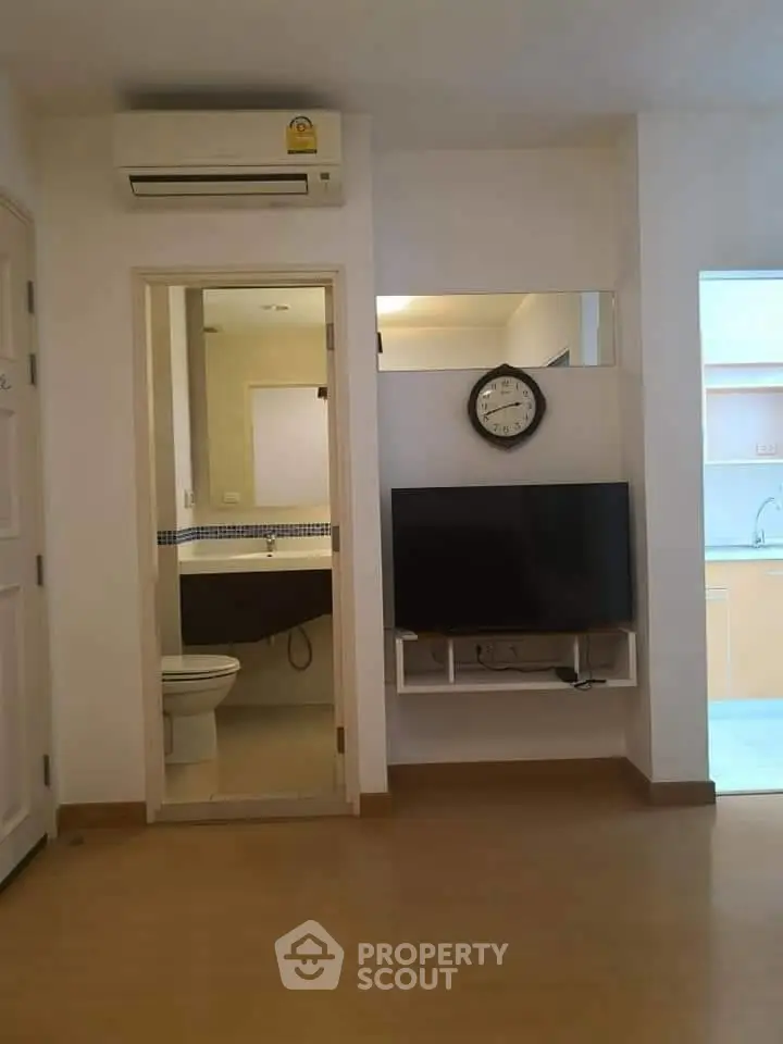 Modern apartment interior with wall-mounted TV and bathroom view, featuring sleek design and efficient use of space.